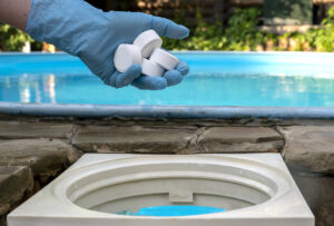 Weiße Poolchemie Tabletten werden in den Pool-Skimmer gelegt, zur Reinigung und Desinfektion des Wassers 