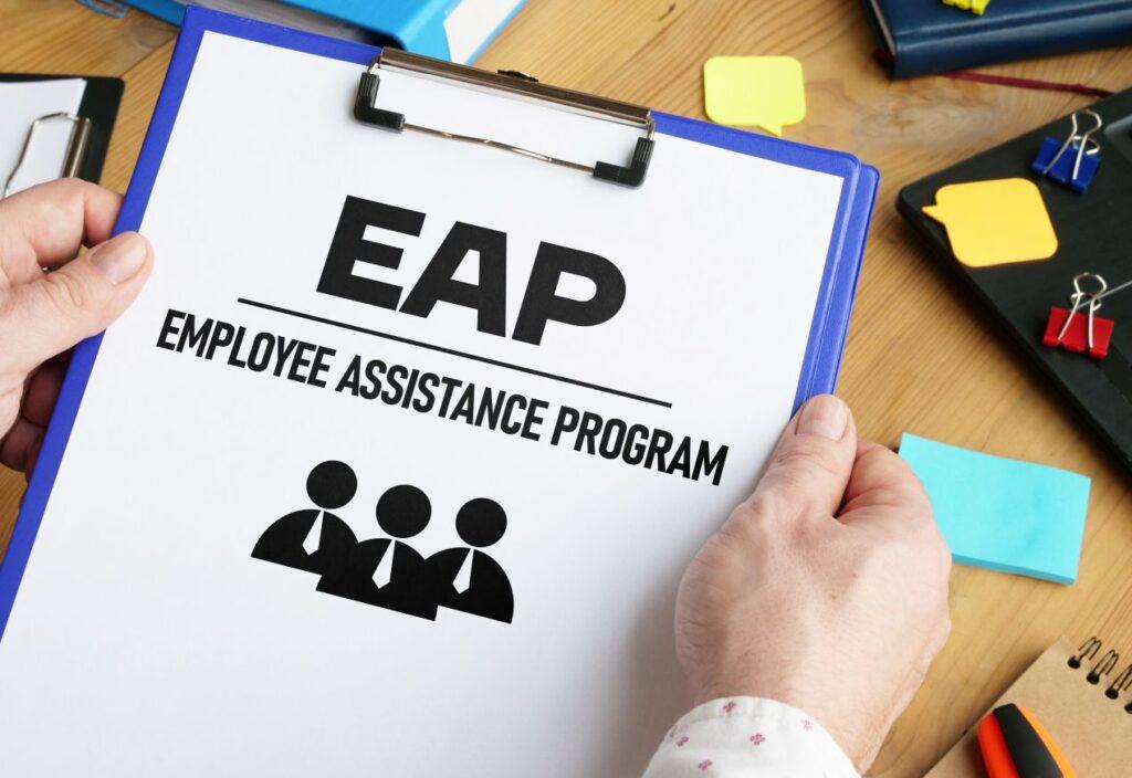 Nahaufnahme eines Klemmbretts mit der Aufschrift „EAP – Employee Assistance Program“. Symbol für betriebliche Mitarbeiterunterstützung und psychische Gesundheit am Arbeitsplatz.