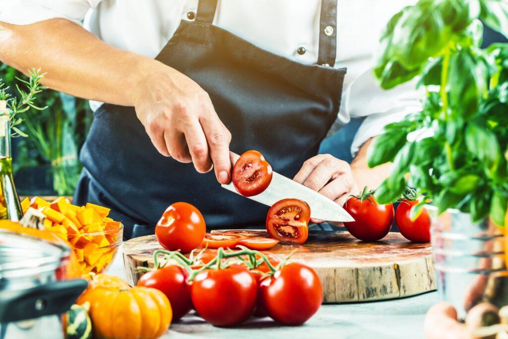 Tomaten schneiden in Aussenkueche mit Gemuese