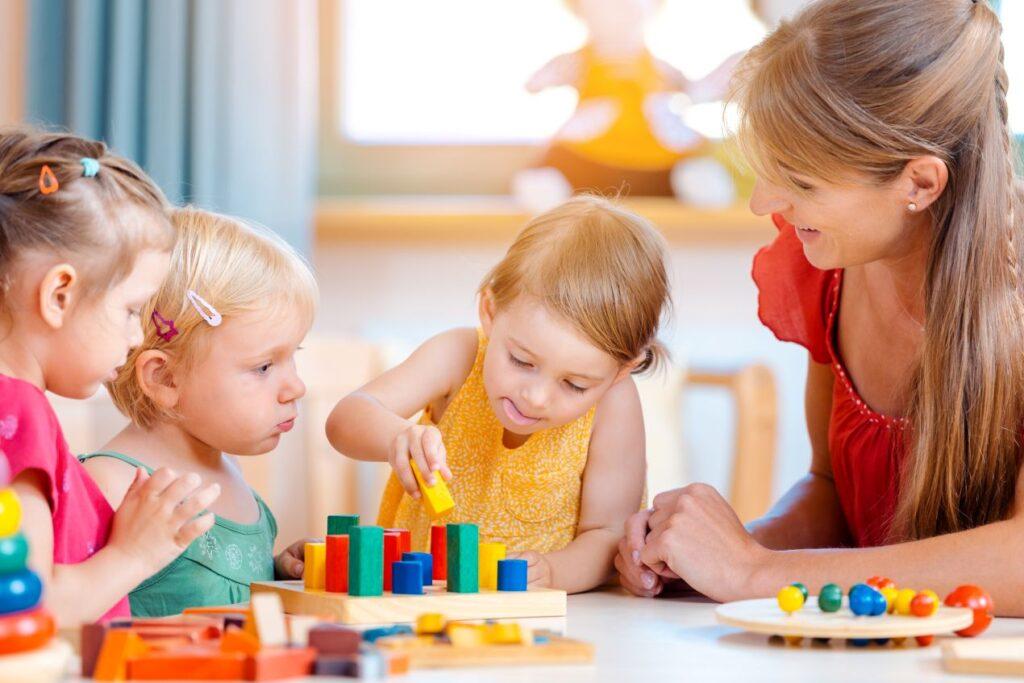 Quereinsteiger Kindergarten beim Foerdern von Kindern mit Lernmaterial im Kita-Alltag